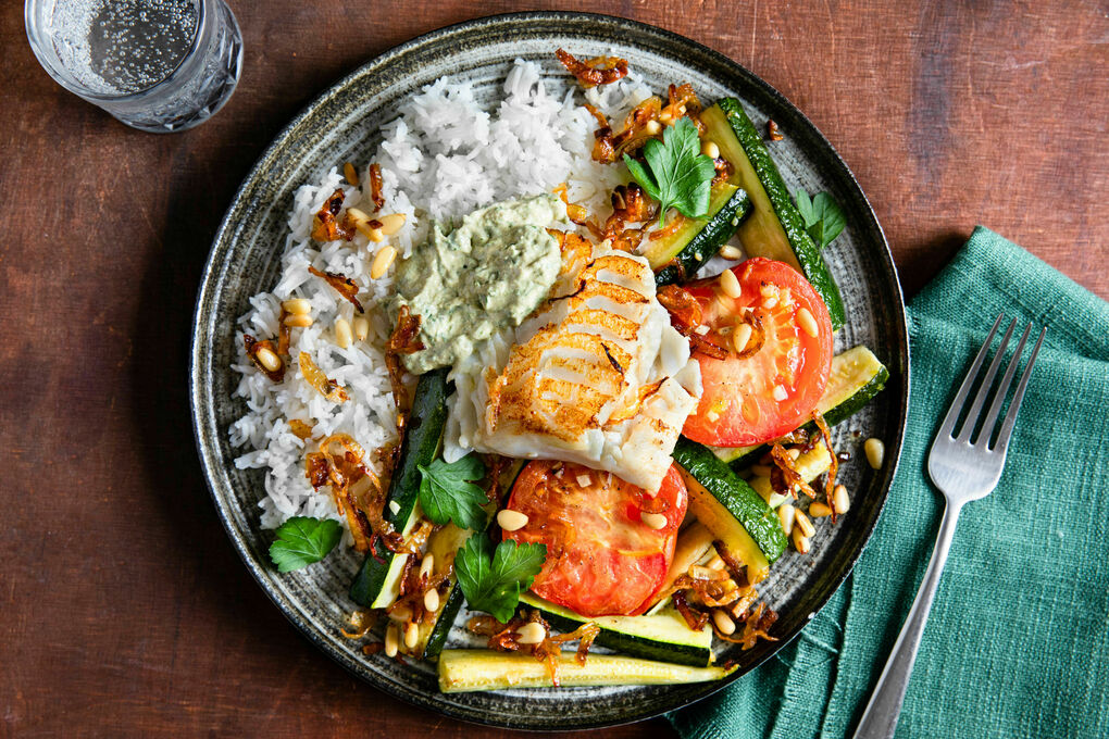 Seehecht mit Tahinisauce und Zucchini dazu gebackene Tomaten, Röstzwiebeln und Reis