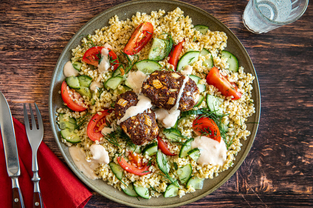 Gebackene Kofta mit Tahinisauce auf Bulgursalat mit Gurke und Tomate