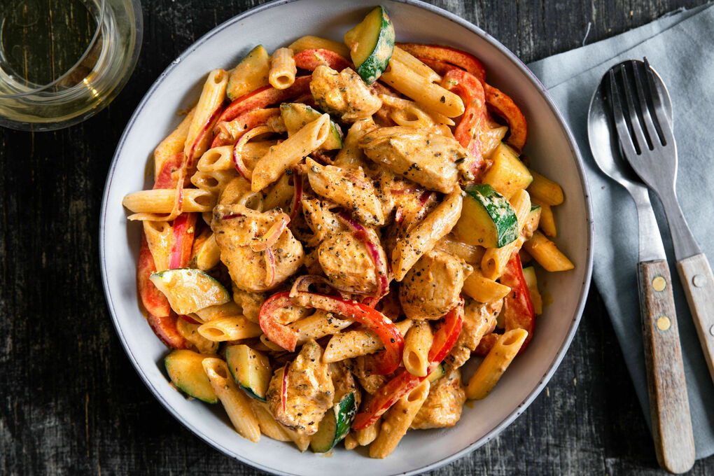 Penne mit zarten Hähnchenwürfeln in cremiger Pesto-Sauce mit Gemüse
