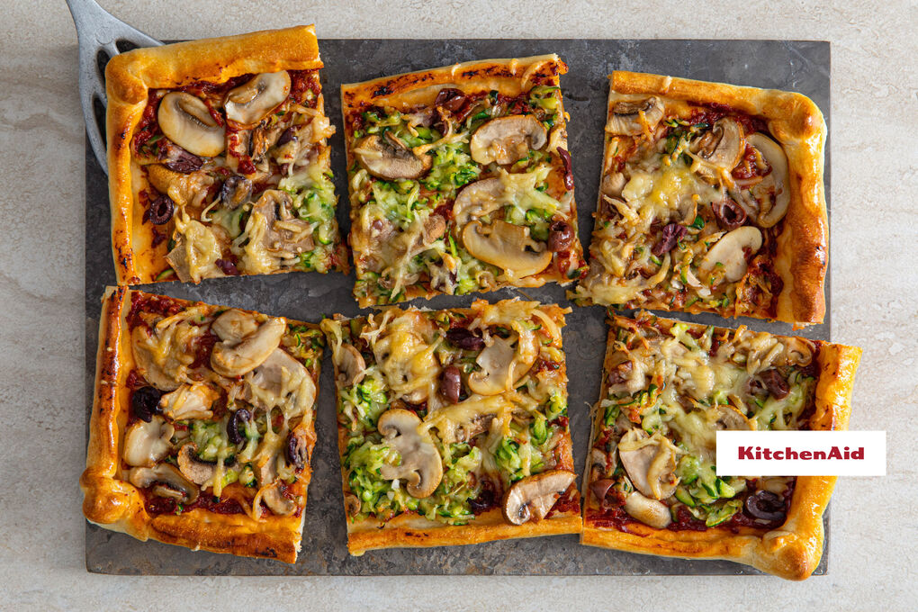 Knusprige Gemüsepizza mit Oliven überbacken mit veganem Reibe-Topping