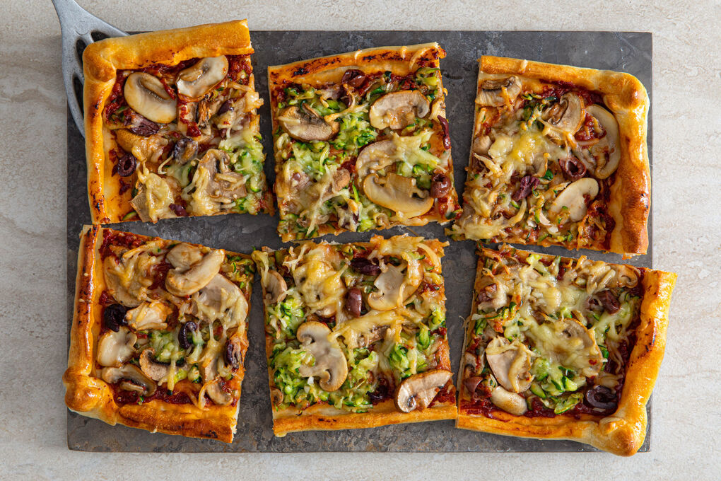 Knusprige Gemüsepizza mit Oliven überbacken mit veganem Reibe-Topping
