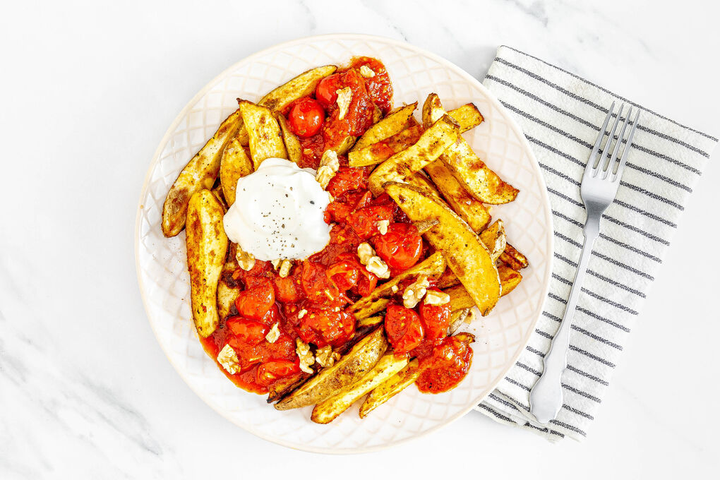 Cajun-Kartoffeln mit Sardellen-Tomaten-Sauce garniert mit saurer Sahne und Walnüssen