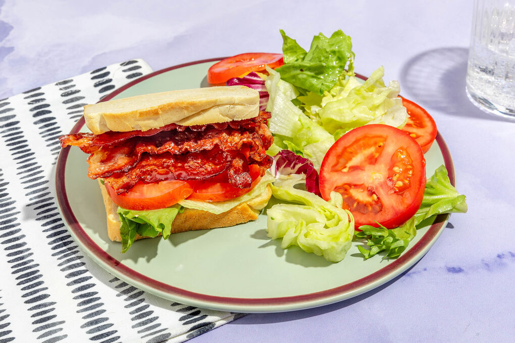 Bacon-Sandwich mit Ahornsirup garniert mit Tomate und buntem Salat