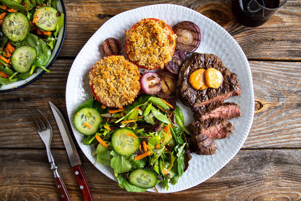 Bio-Steak mit BBQ-Butter und Röstzwiebeln dazu Tomaten mit Bröselhaube und Salat
