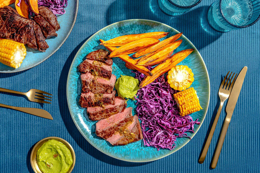 Saftiges Bio-Rindersteak mit Orangensauce dazu Süßkartoffeln, Rotkohl und Cajun-Mais