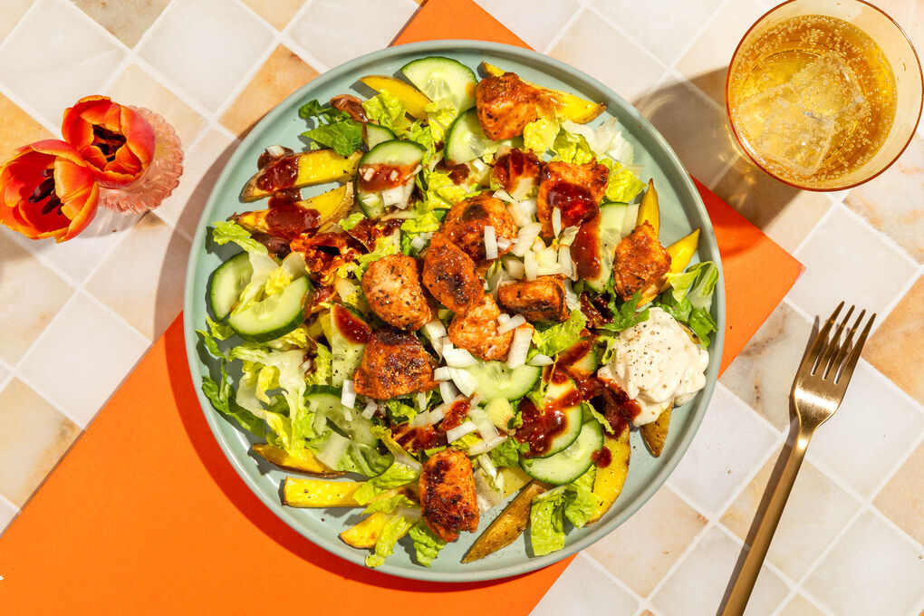 Gebratenes Hähnchen mit Erdnusssauce auf Pommes mit Romanasalat und Gurke