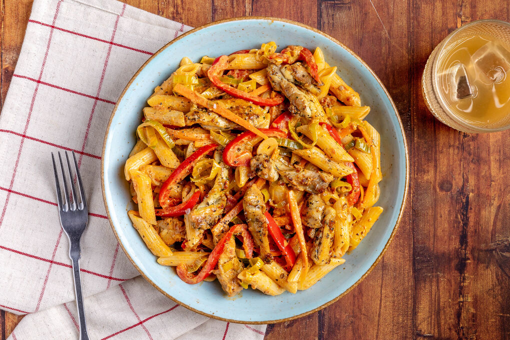 Penne mit zarten Hähnchenwürfeln in cremiger Pesto-Sauce mit Gemüse