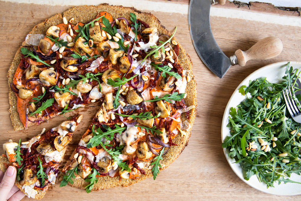 Quinoapizza mit Mozzarella & Pilzen garniert mit Rucola und Pinienkernen