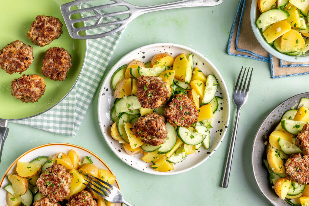 Fleischbällchen auf warmem Kartoffelsalat mit frischer Gurke und Petersilie