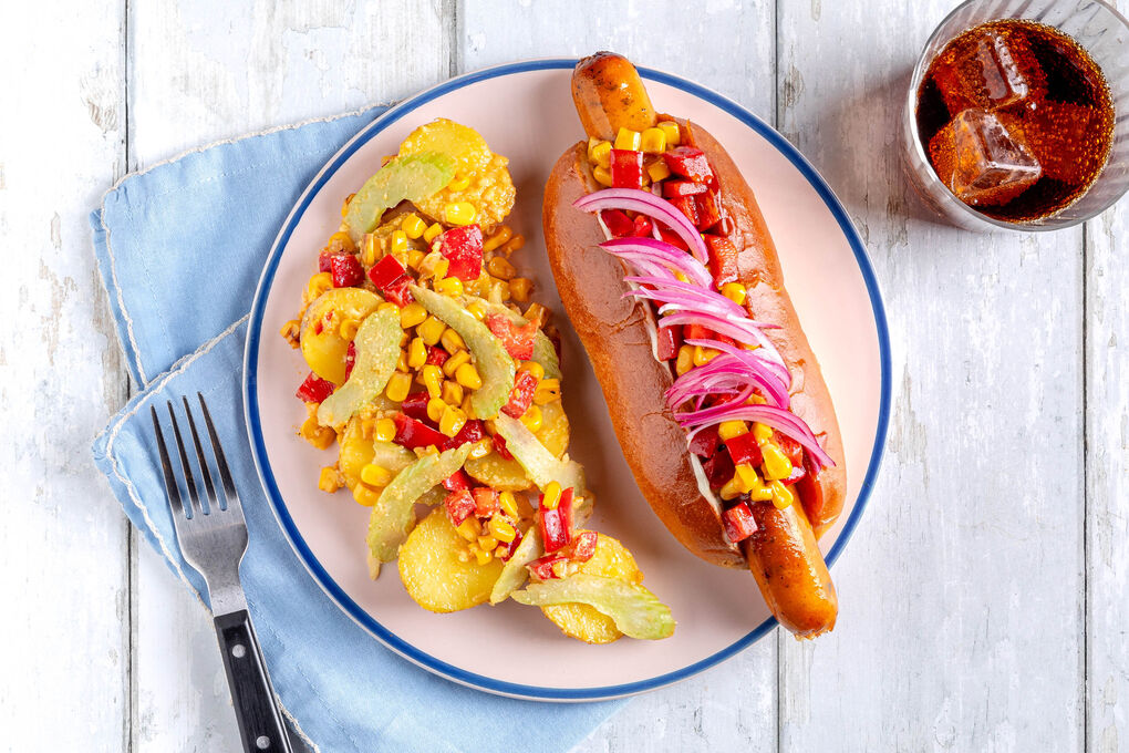Hotdog mit Geflügelwurst und Mais-Salsa dazu Kartoffel-Erdnuss-Salat