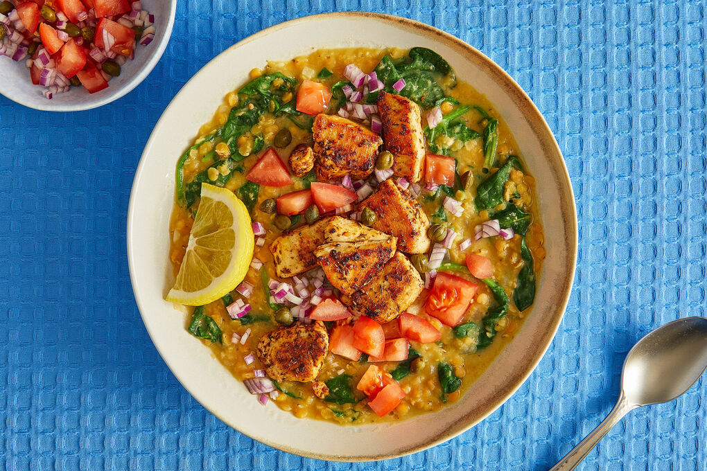 Saftige Hähnchenwürfel an Spinat-Linsen-Topf aromatisch mit Tomaten, Kapern und Zitrone