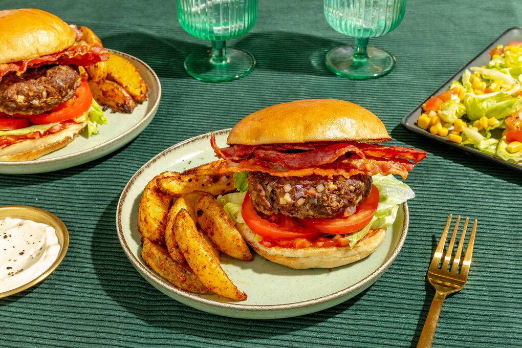 Burger de luxe mit Bio-Rind und Bacon dazu Kartoffelwedges und Salat mit Mais