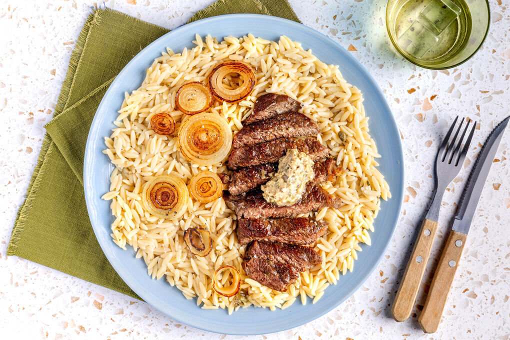 Bio-Rindersteak mit Kapernbutter mit karamellisierten Zwiebeln auf Käse-Risoni