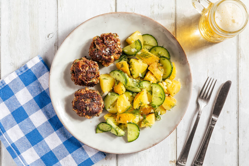 Rinderbällchen auf warmem Kartoffelsalat mit frischen Gurken und Petersilie