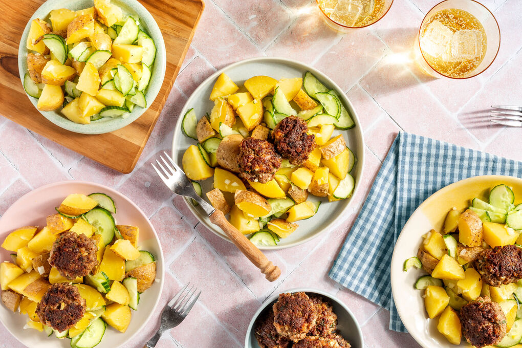 Rindfleischbällchen auf Kartoffelsalat mit frischer Gurke und Petersilie