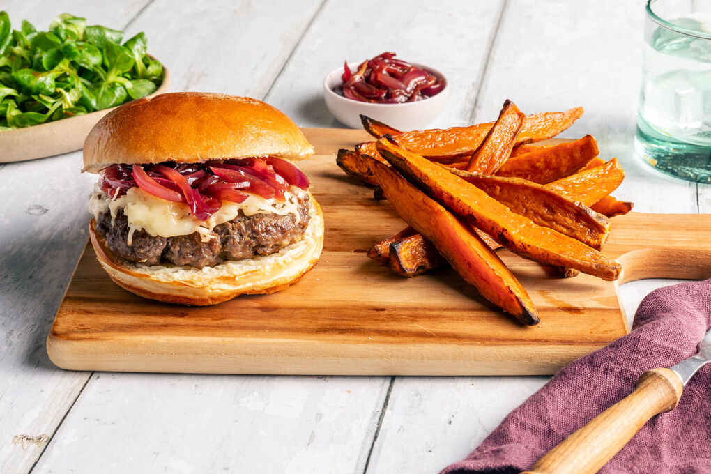 Saftiger Burger mit Käse und Zwiebelmarmelade dazu Süßkartoffelpommes und Feldsalat