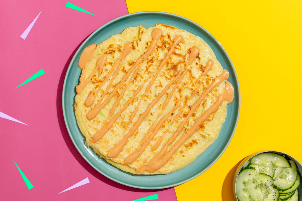 Herzhafte Okonomiyaki-Pfannkuchen serviert mit frischem Gurkensalat