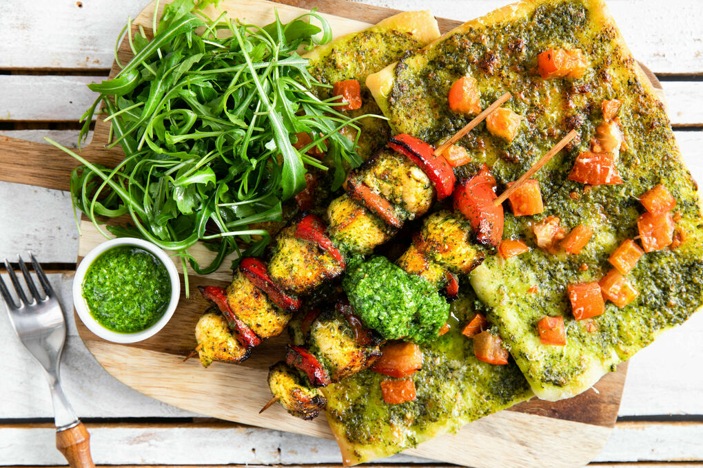 Paprika-Hähnchen-Spieße mit Rucola auf knusprigem Pizzabrot mit Pesto
