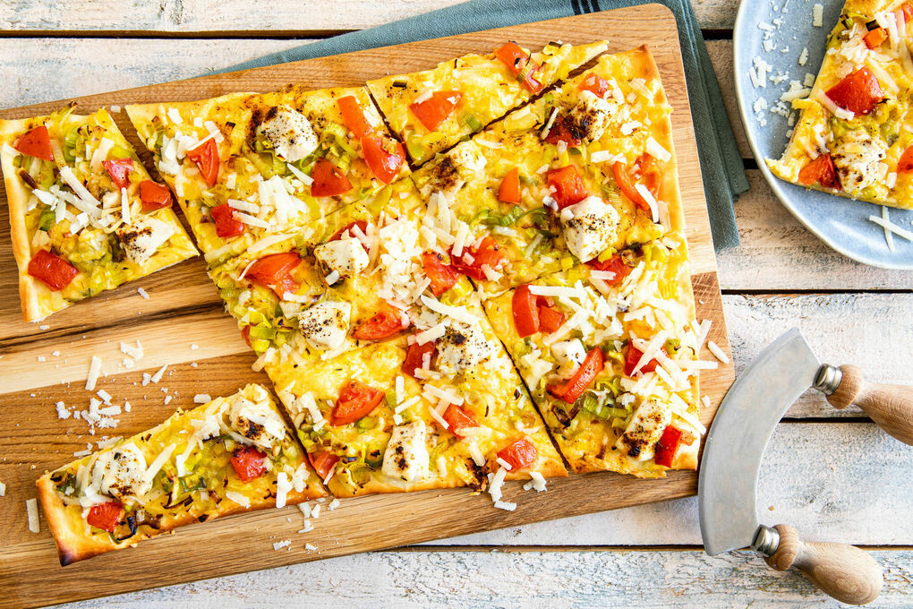 Hähnchen-Käse-Pizza mit gebratenem Lauch und Tomate