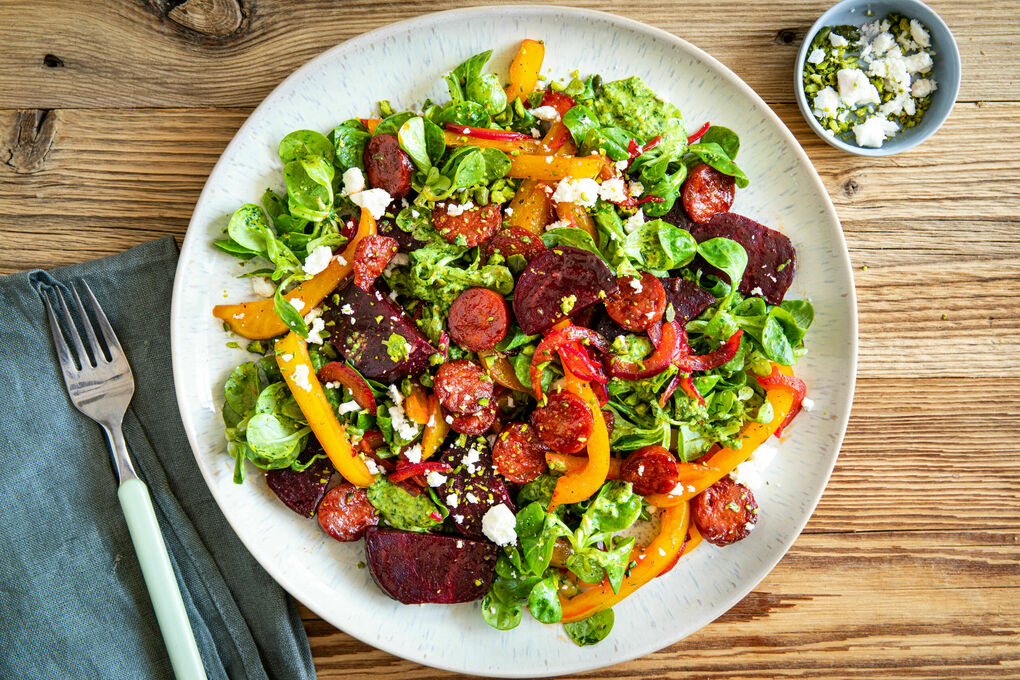 Kross gebratene Chorizo und Feta auf buntem Salat mit Pistaziendressing