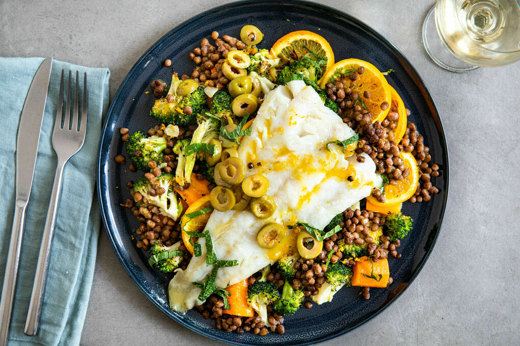 Seehecht auf Orange gebacken serviert auf Linsen-Gemüse-Salat mit Oliven