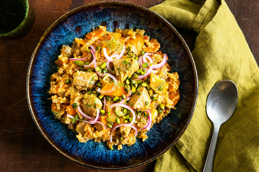 Fenchel-Karotten-Bulgur mit Schwein garniert mit roten Zwiebeln und Pistazien